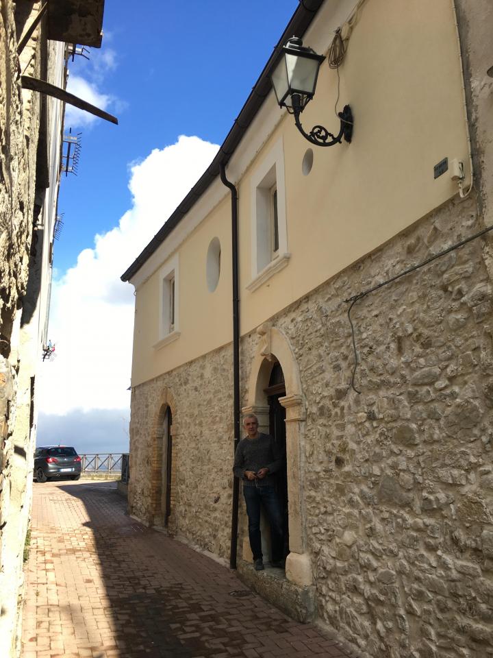 Stone house with arched door in narrow street with blue sky behind