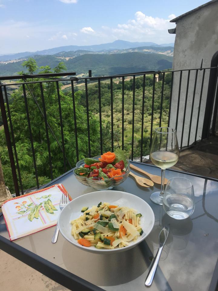 A table laid with pasta, salad, wine and a retro napkin