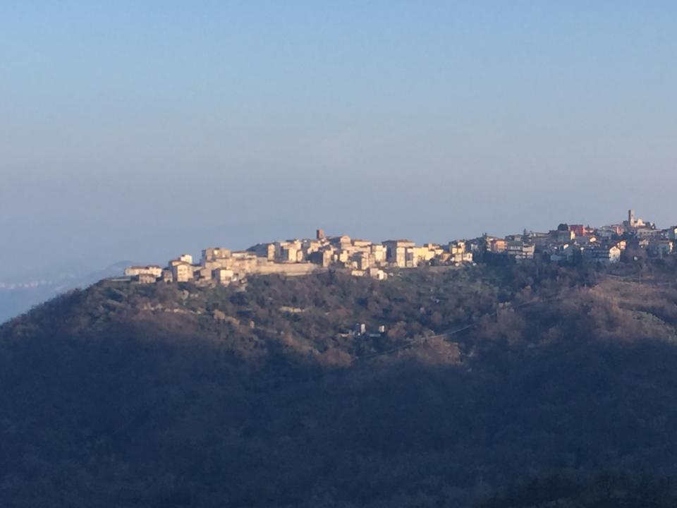 A distant view of a hill top village in misty shades of grey and blue