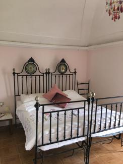 Large ornate wrought iron bed against a light pink wall 